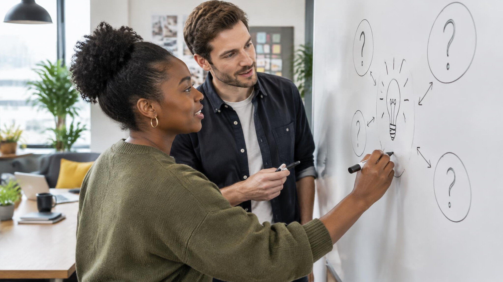 Colleagues writing scripts together on a whiteboard
